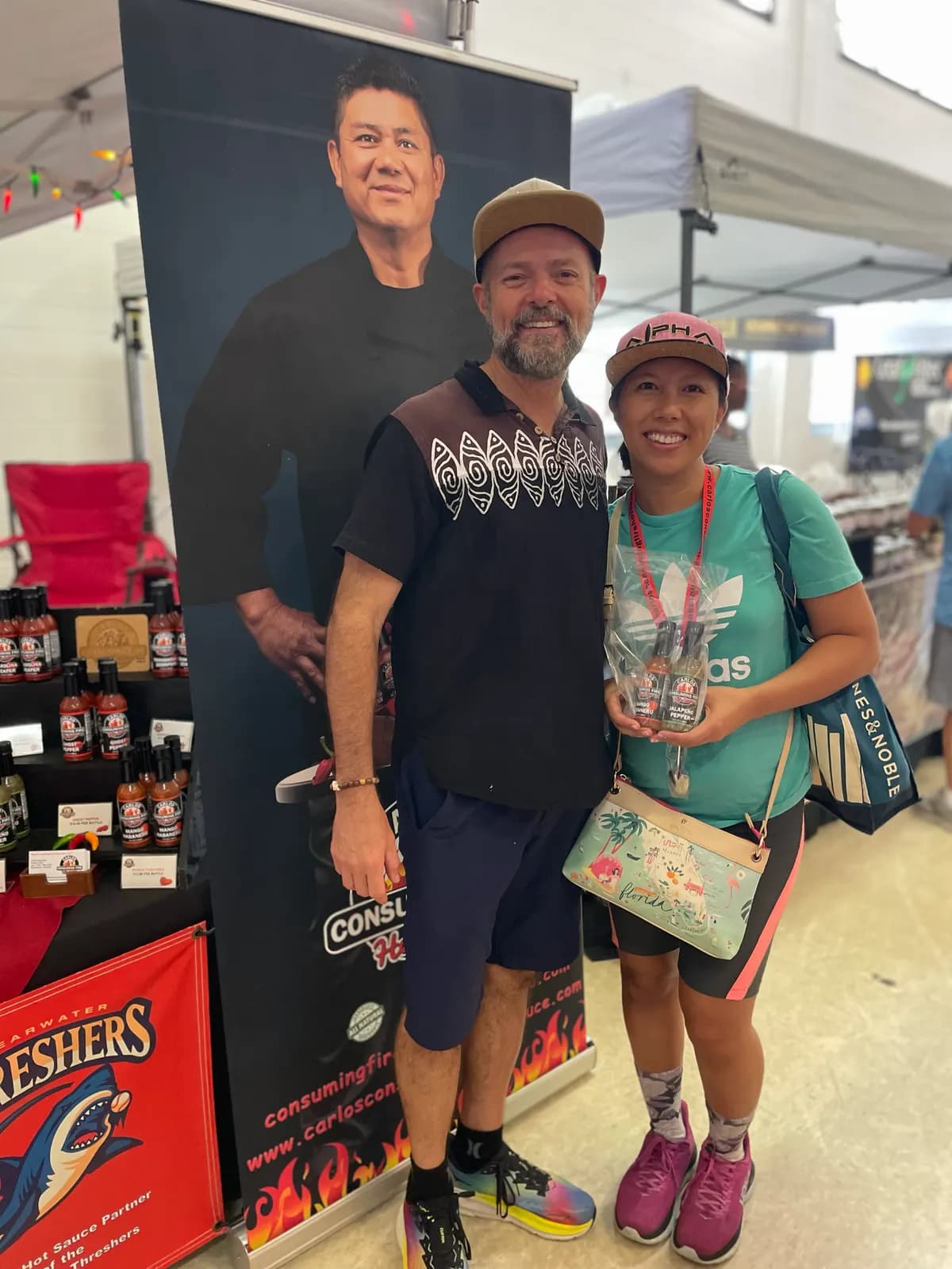 Couple posing with a wrapped gift pack of mini sauce bottles at a market